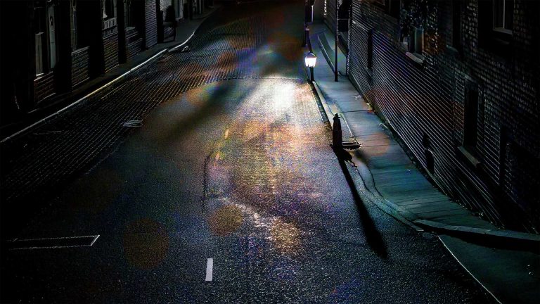 image of a dark rainy street at night with street light seen from above