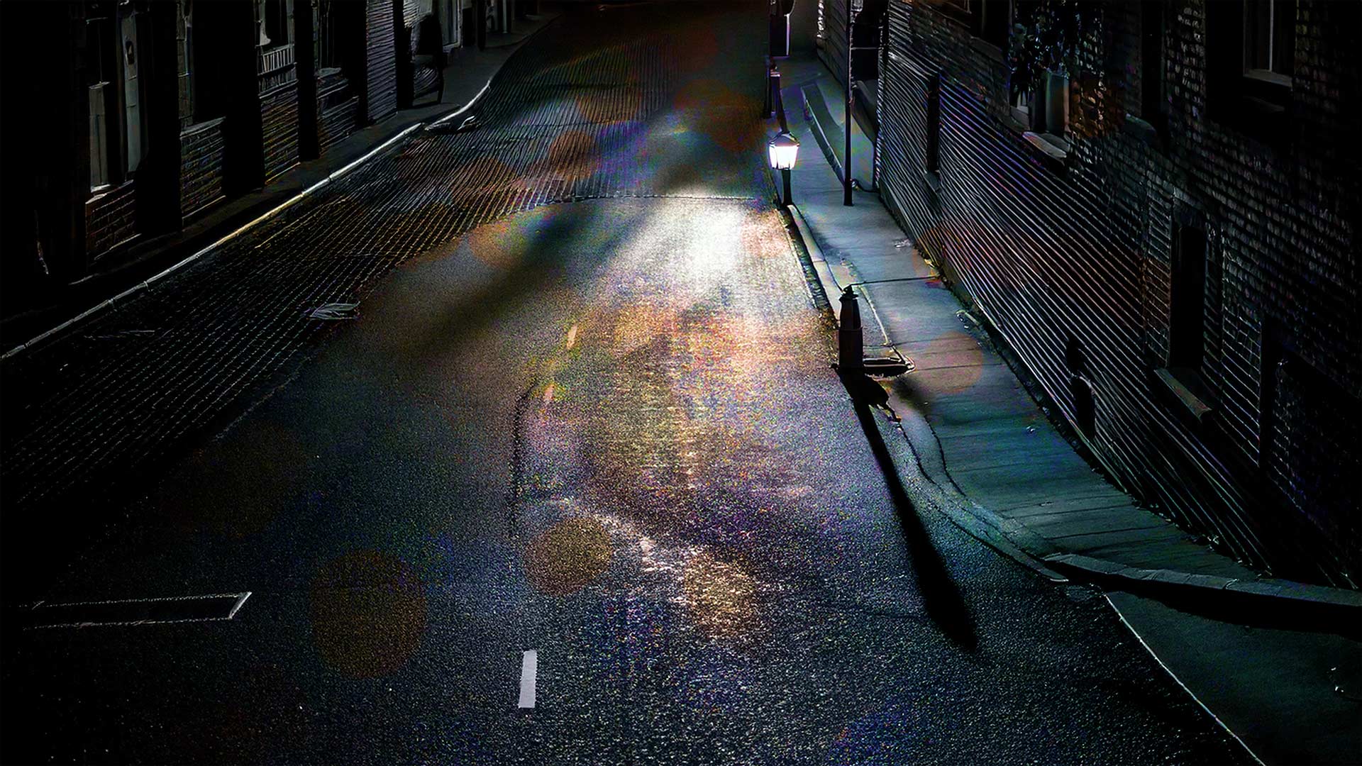 image of a dark rainy street at night with street light seen from above